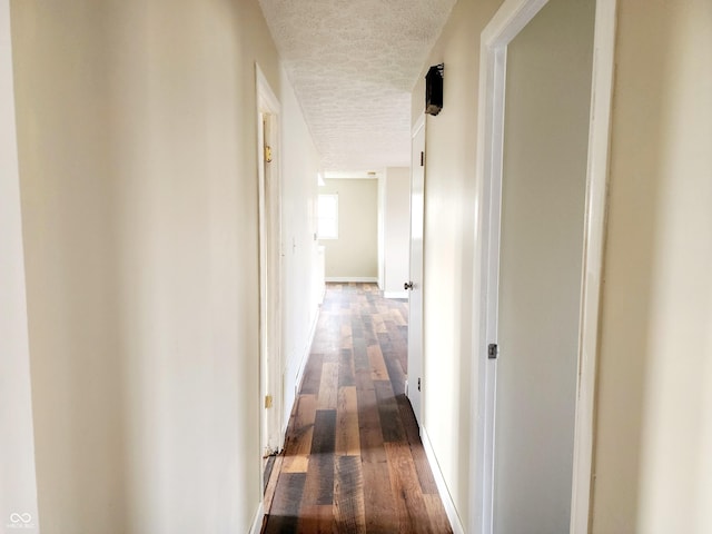 hall featuring a textured ceiling and dark wood-type flooring