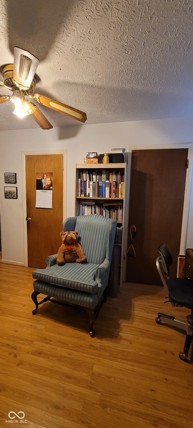 sitting room featuring ceiling fan, a textured ceiling, and hardwood / wood-style flooring