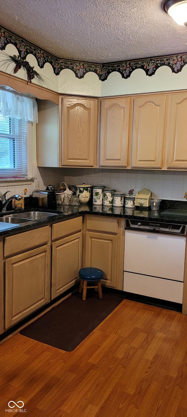 kitchen featuring a textured ceiling, white dishwasher, sink, light brown cabinets, and hardwood / wood-style floors