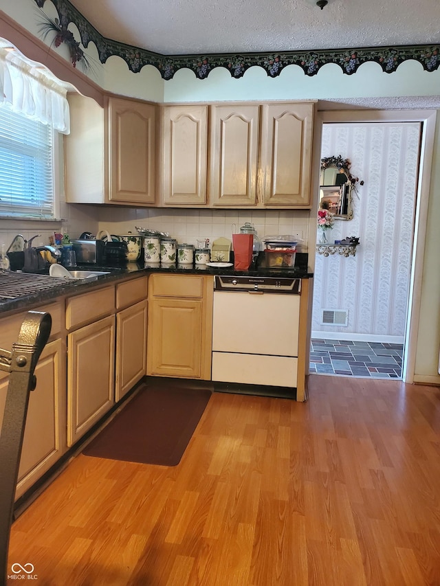 kitchen featuring light brown cabinetry, light wood-type flooring, tasteful backsplash, a textured ceiling, and white dishwasher