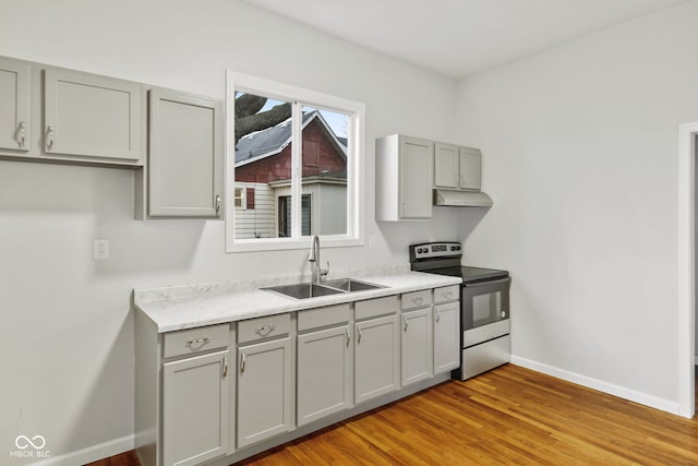 kitchen featuring gray cabinetry, light hardwood / wood-style floors, stainless steel electric range oven, and sink