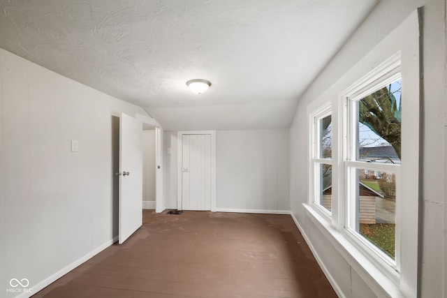 spare room with dark wood-type flooring and lofted ceiling