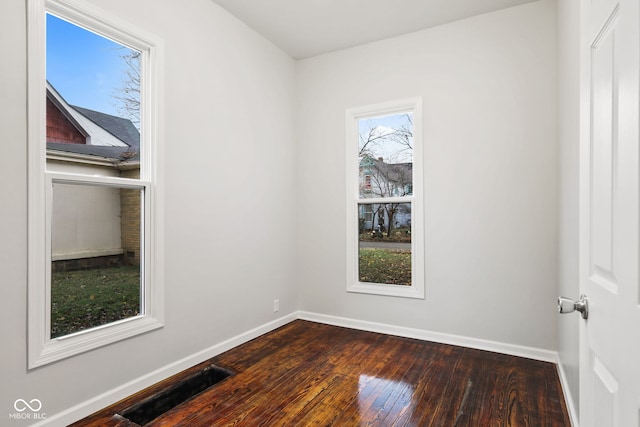 spare room with dark hardwood / wood-style floors and plenty of natural light