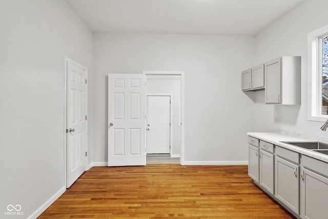 kitchen featuring gray cabinetry, sink, and light hardwood / wood-style floors