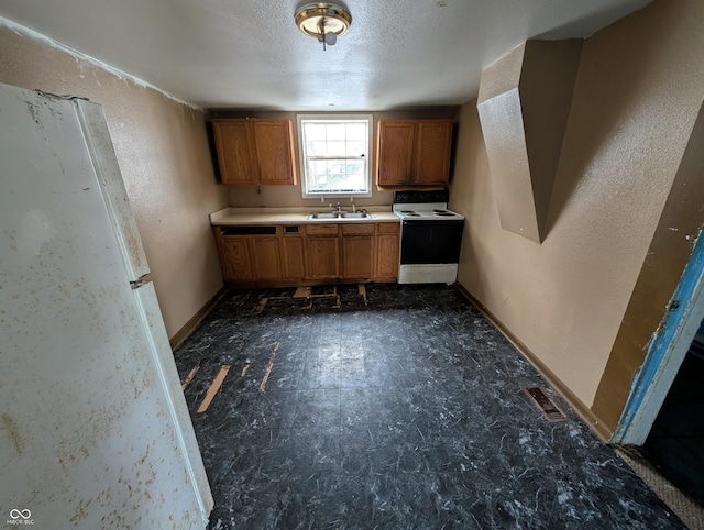 kitchen with a textured ceiling, white range with electric stovetop, and sink