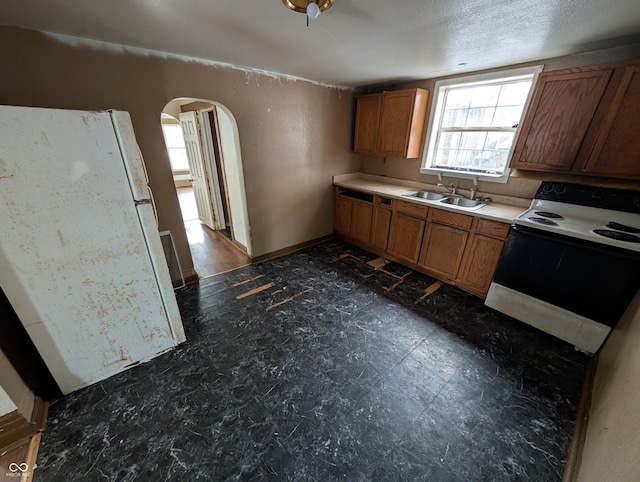 kitchen with a textured ceiling, electric range, and sink