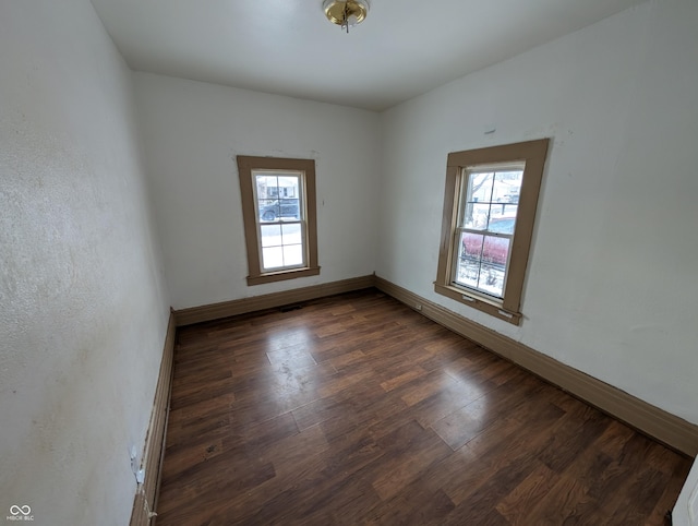 spare room with a healthy amount of sunlight, dark hardwood / wood-style flooring, and a baseboard radiator