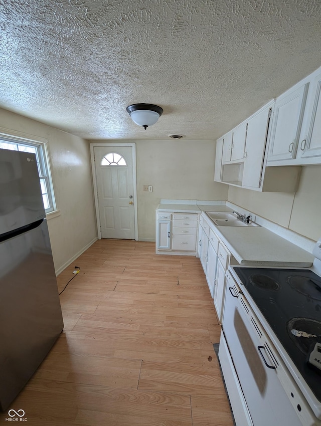 kitchen featuring white cabinetry, sink, white range with electric cooktop, stainless steel fridge, and light hardwood / wood-style floors