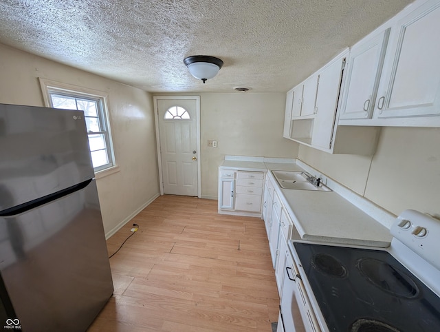 kitchen with sink, white electric range, stainless steel fridge, light hardwood / wood-style floors, and white cabinets