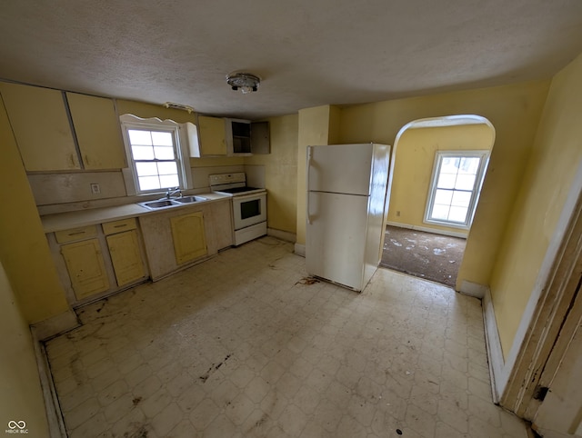 kitchen featuring a textured ceiling, white appliances, and sink