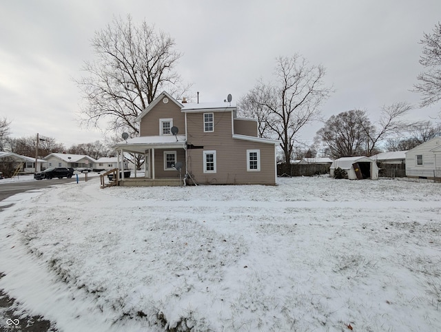 snow covered property with a porch and a storage shed