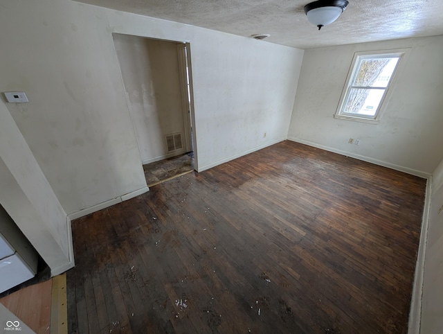 unfurnished room with a textured ceiling and dark wood-type flooring