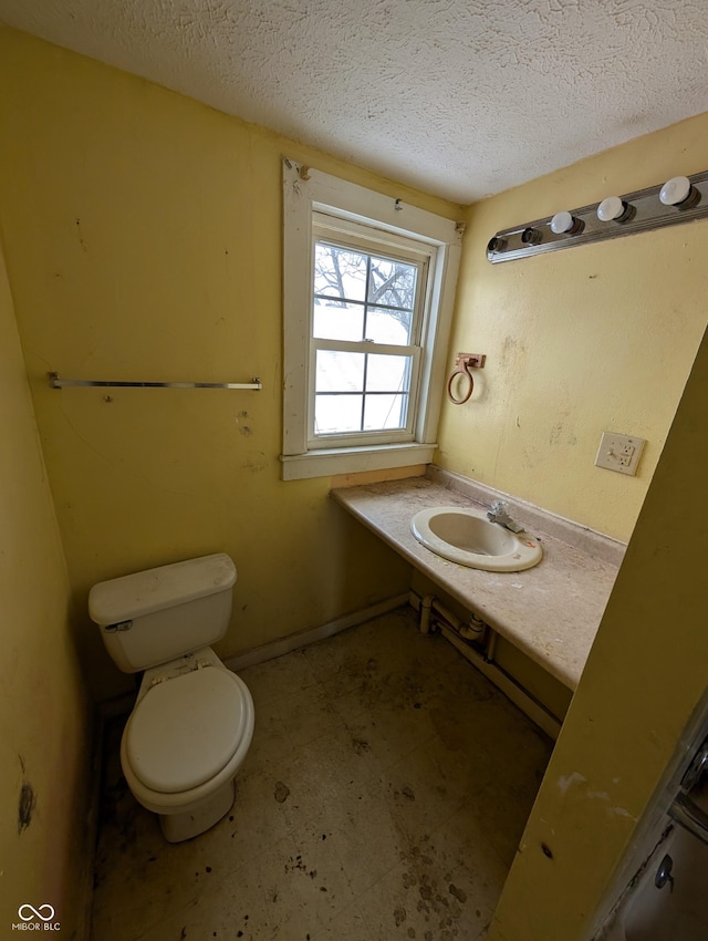 bathroom featuring a textured ceiling, toilet, and sink