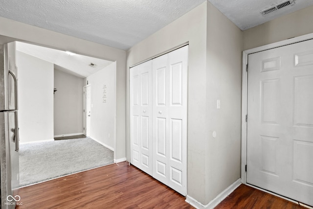 hall with a textured ceiling and dark hardwood / wood-style floors