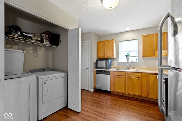 washroom with washer and clothes dryer, wood-type flooring, a textured ceiling, and sink