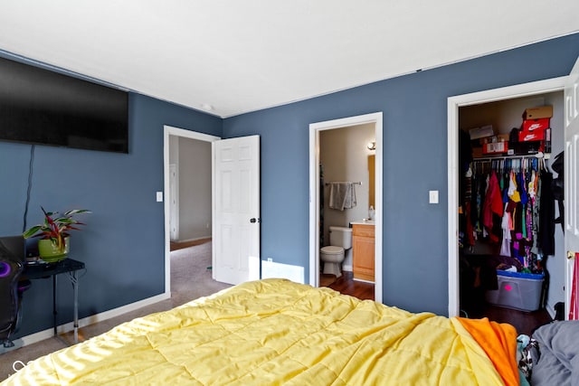 bedroom with dark colored carpet, ensuite bath, a walk in closet, and a closet