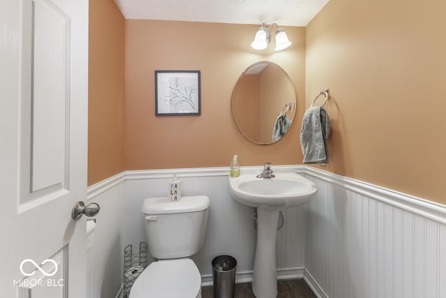 bathroom featuring wood-type flooring, an inviting chandelier, toilet, and sink