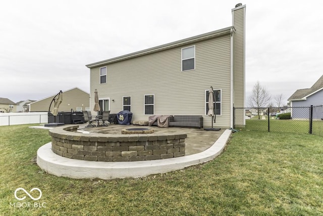 back of property with a fire pit, a patio, and a lawn