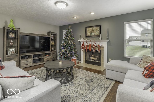 living room featuring a textured ceiling, dark hardwood / wood-style floors, and a tiled fireplace