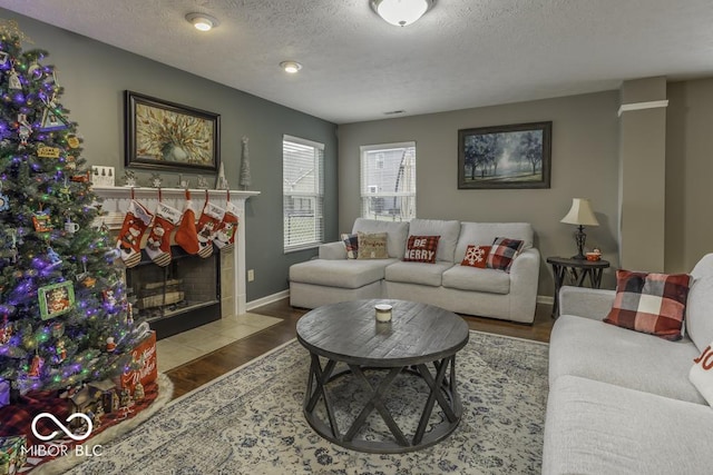 living room with hardwood / wood-style floors, a textured ceiling, and a tile fireplace