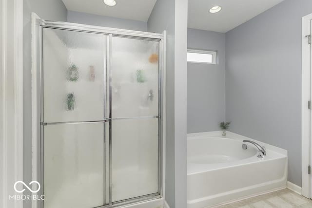 bathroom with wood-type flooring and shower with separate bathtub