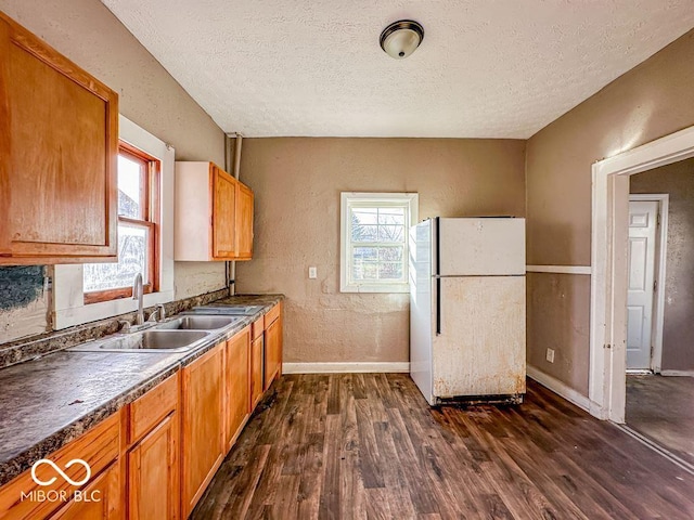 kitchen with a textured ceiling, white fridge, dark hardwood / wood-style flooring, and sink