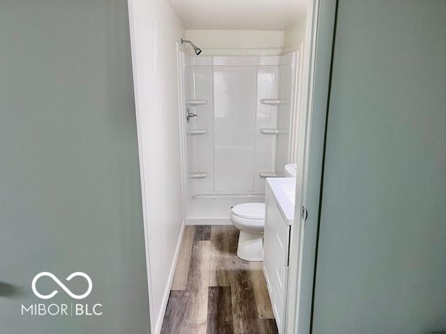 bathroom with hardwood / wood-style flooring, a shower, toilet, and vanity