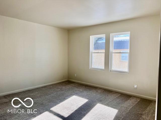 spare room with dark colored carpet