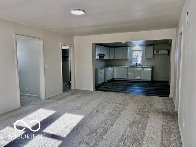 unfurnished living room featuring light colored carpet and sink