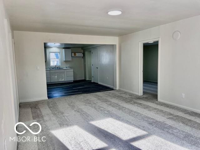 unfurnished living room featuring sink and carpet flooring