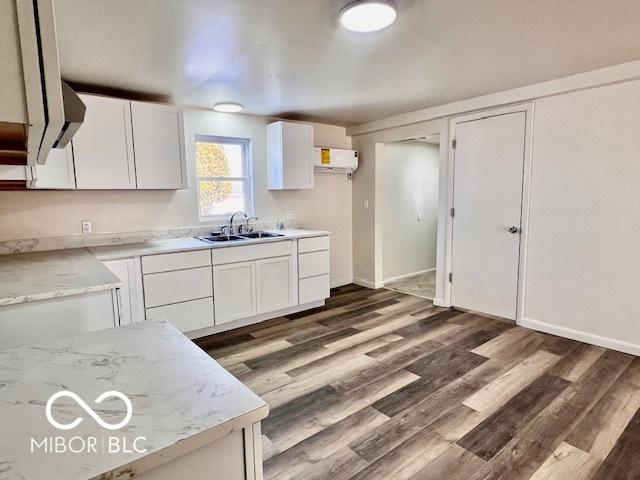 kitchen with white cabinetry, dark hardwood / wood-style floors, light stone counters, and sink