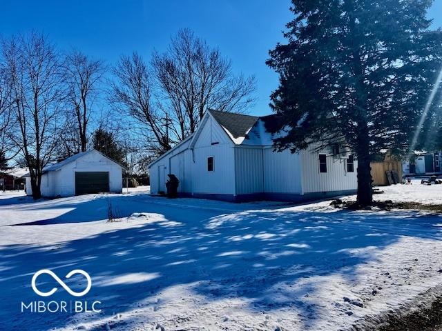 snow covered property with an outdoor structure and a garage