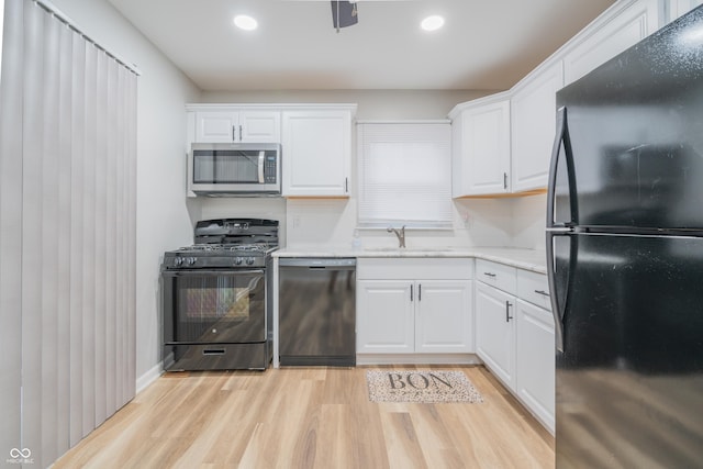 kitchen with black appliances, light hardwood / wood-style floors, white cabinetry, and tasteful backsplash