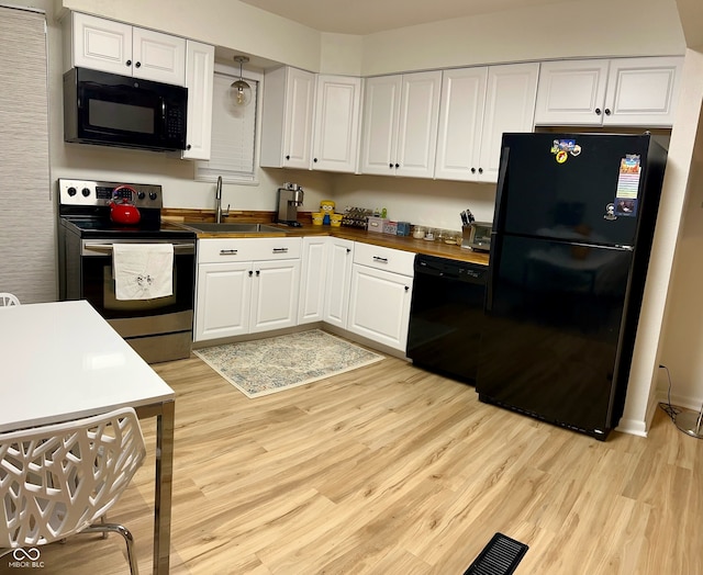 kitchen featuring butcher block counters, white cabinetry, sink, black appliances, and light wood-type flooring