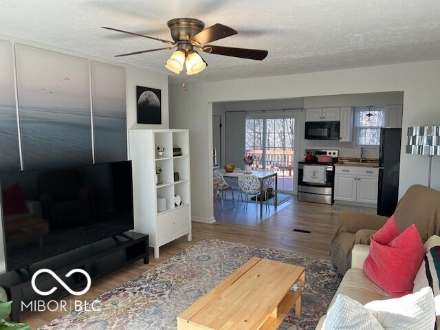 living room featuring a textured ceiling, a ceiling fan, and wood finished floors