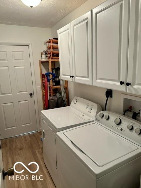 washroom featuring a textured ceiling, wood finished floors, washing machine and dryer, and cabinet space