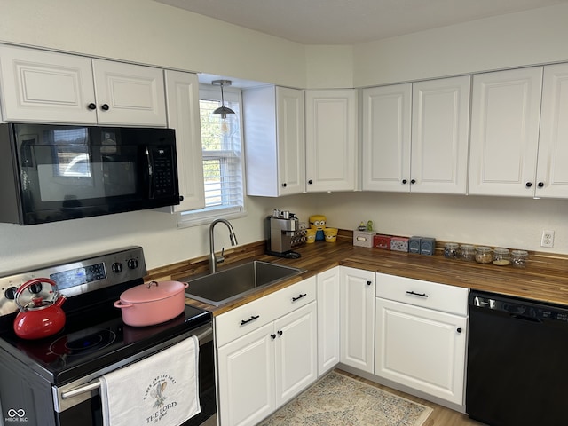 kitchen with black appliances, a sink, wooden counters, and white cabinetry