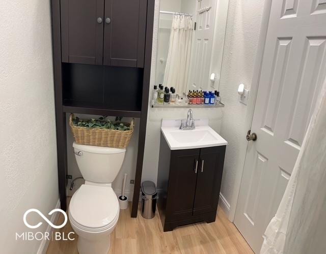 bathroom featuring a textured wall, vanity, toilet, and wood finished floors