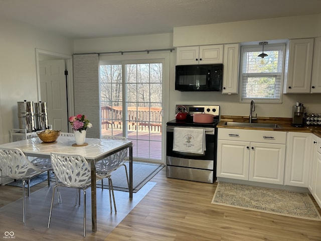 kitchen with stainless steel electric range oven, a healthy amount of sunlight, a sink, light wood-type flooring, and black microwave