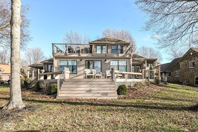 rear view of property featuring a balcony, a deck, and a lawn