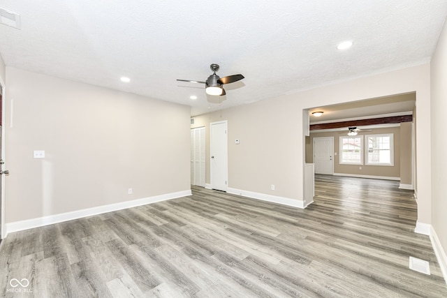 empty room with light wood-type flooring, a textured ceiling, and ceiling fan