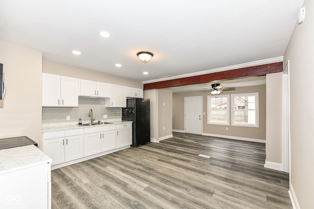 kitchen with tasteful backsplash, white cabinetry, black refrigerator, and sink