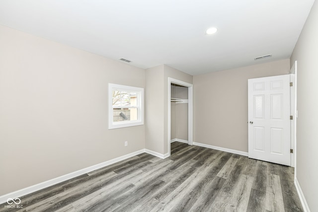 unfurnished bedroom with dark hardwood / wood-style flooring and a closet