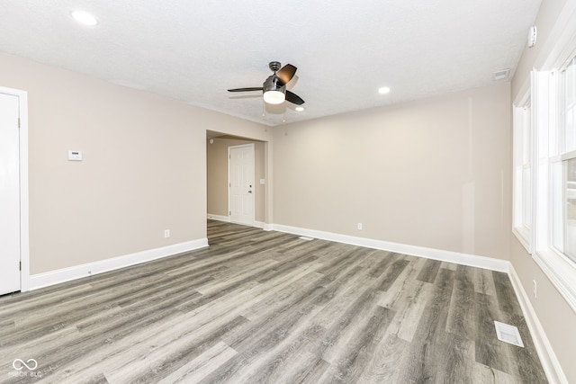 empty room with hardwood / wood-style flooring, ceiling fan, a textured ceiling, and a wealth of natural light