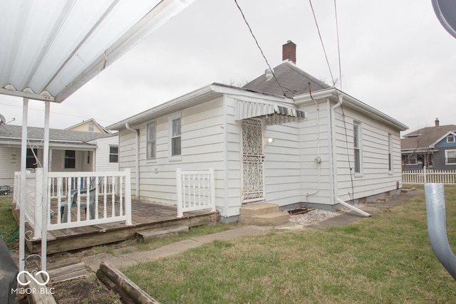 back of house with a wooden deck and a lawn