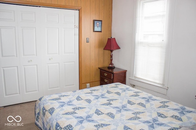 bedroom with carpet, wood walls, and a closet