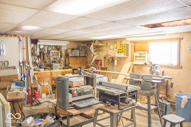 interior space featuring a workshop area, a drop ceiling, and concrete floors