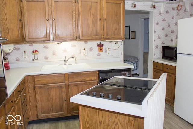 kitchen with sink, black appliances, and light hardwood / wood-style flooring