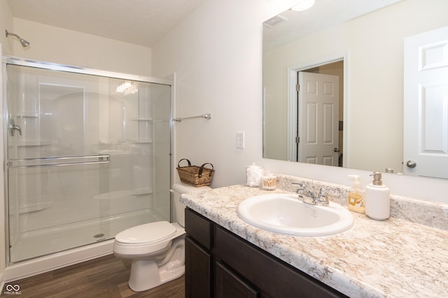 bathroom with walk in shower, a textured ceiling, vanity, hardwood / wood-style flooring, and toilet