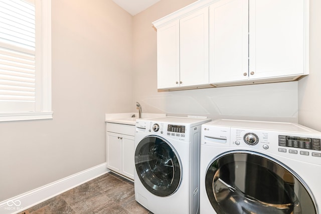 laundry area featuring washing machine and dryer, cabinet space, and baseboards